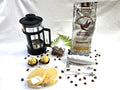 Bag of Hummingbird Coffee Roasters Oomph! coffee, French press, cookies, and chocolate truffles on a white background
