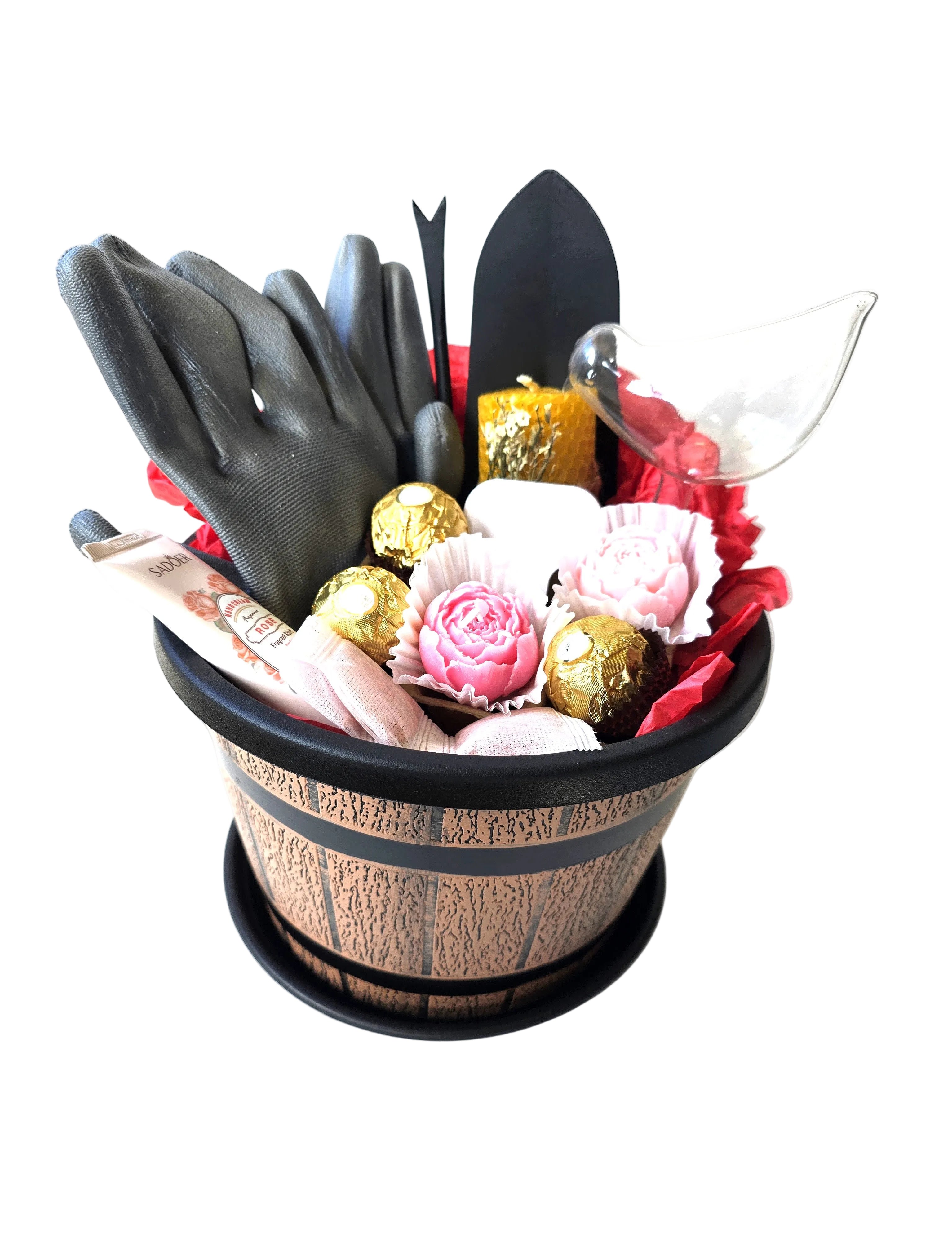 Gardening tools, gloves, and flowers arranged in a decorative pot on a white background